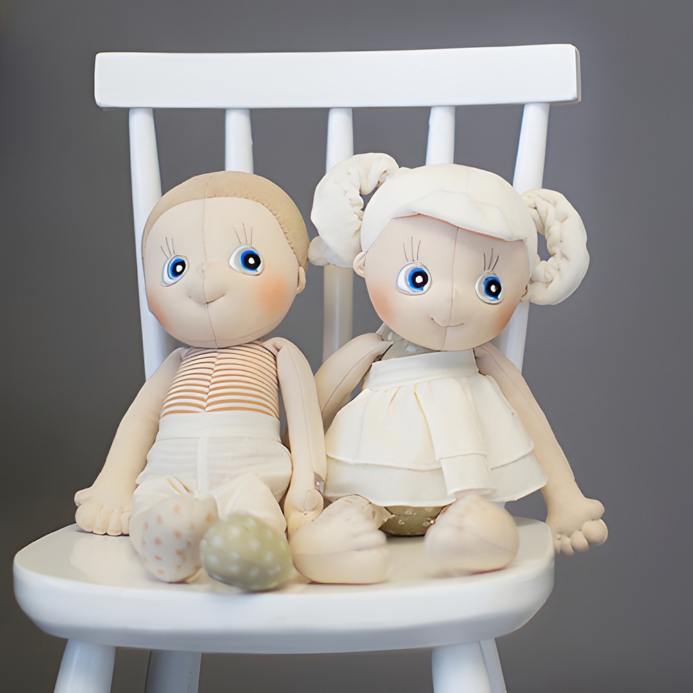 The Rubens EcoBuds dolls Aspen and Hazel sitting on a white chair