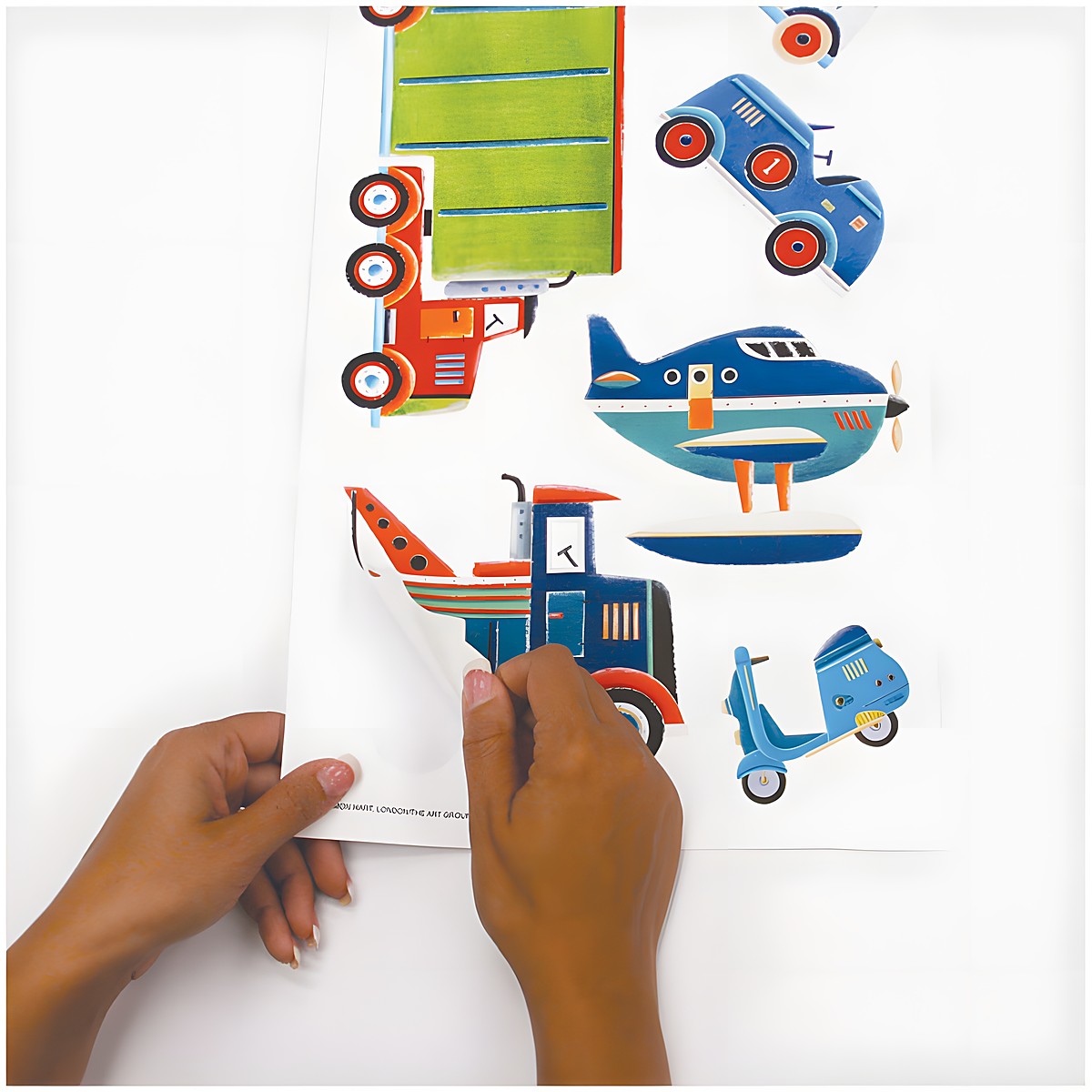 RoomMates wall decal Transportation, hands peeling a seaplane motif off the backing sheet, usage example