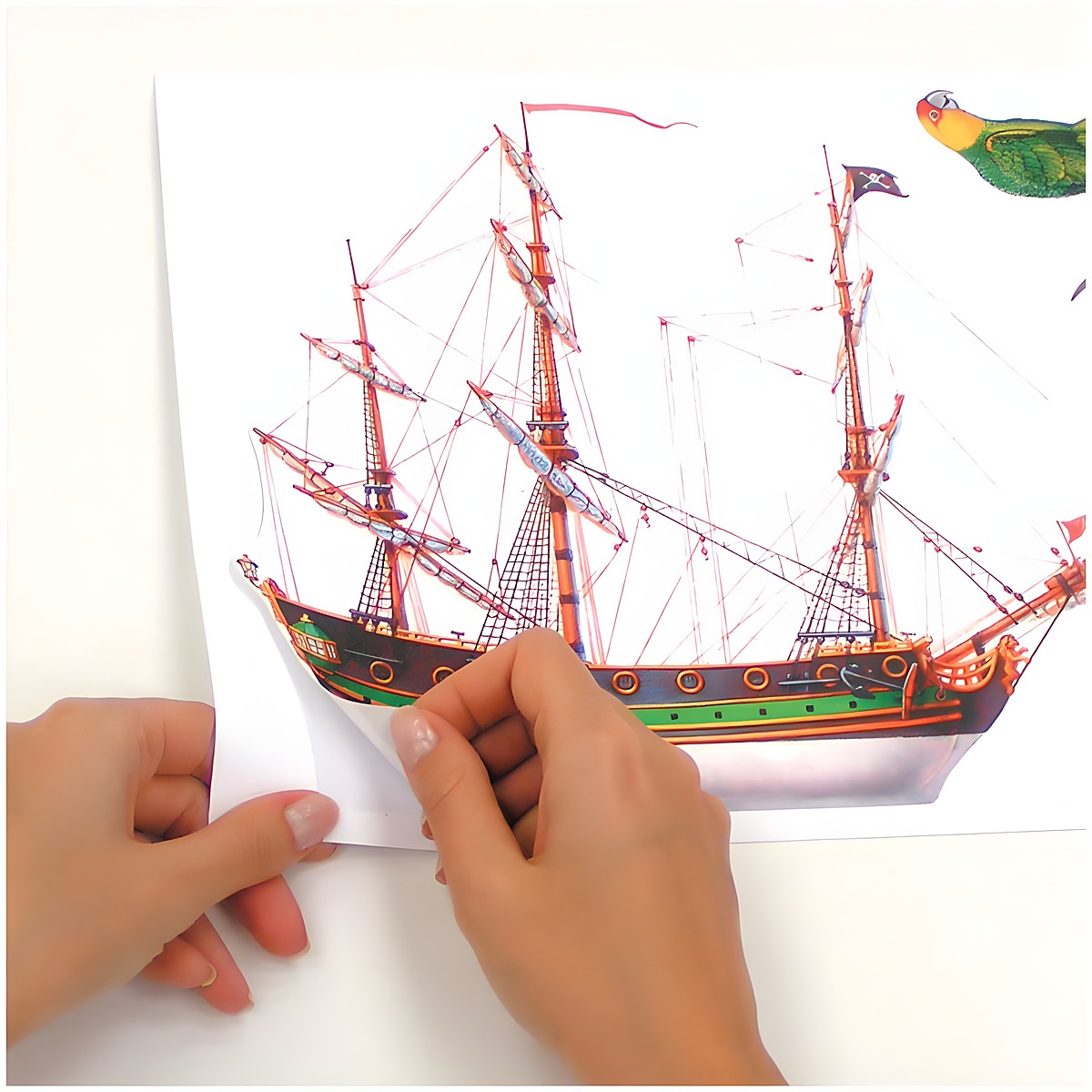 RoomMates Wandsticker Pirates, Hände lösen ein Segelschiff-Motiv vom Trägerbogen, Anwendungsbeispiel