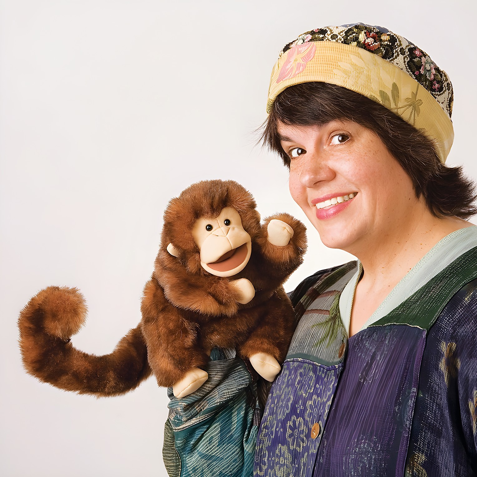 Folkmanis Handpuppe Affe mit braunem Fell und beweglichem Maul, von einer Frau mit Mütze über der Schulter geführt.