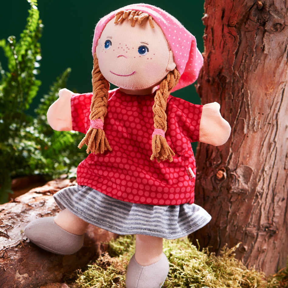 HABA baby hand puppet Gretelchen, lifestyle photo in the forest by a moss-covered tree trunk