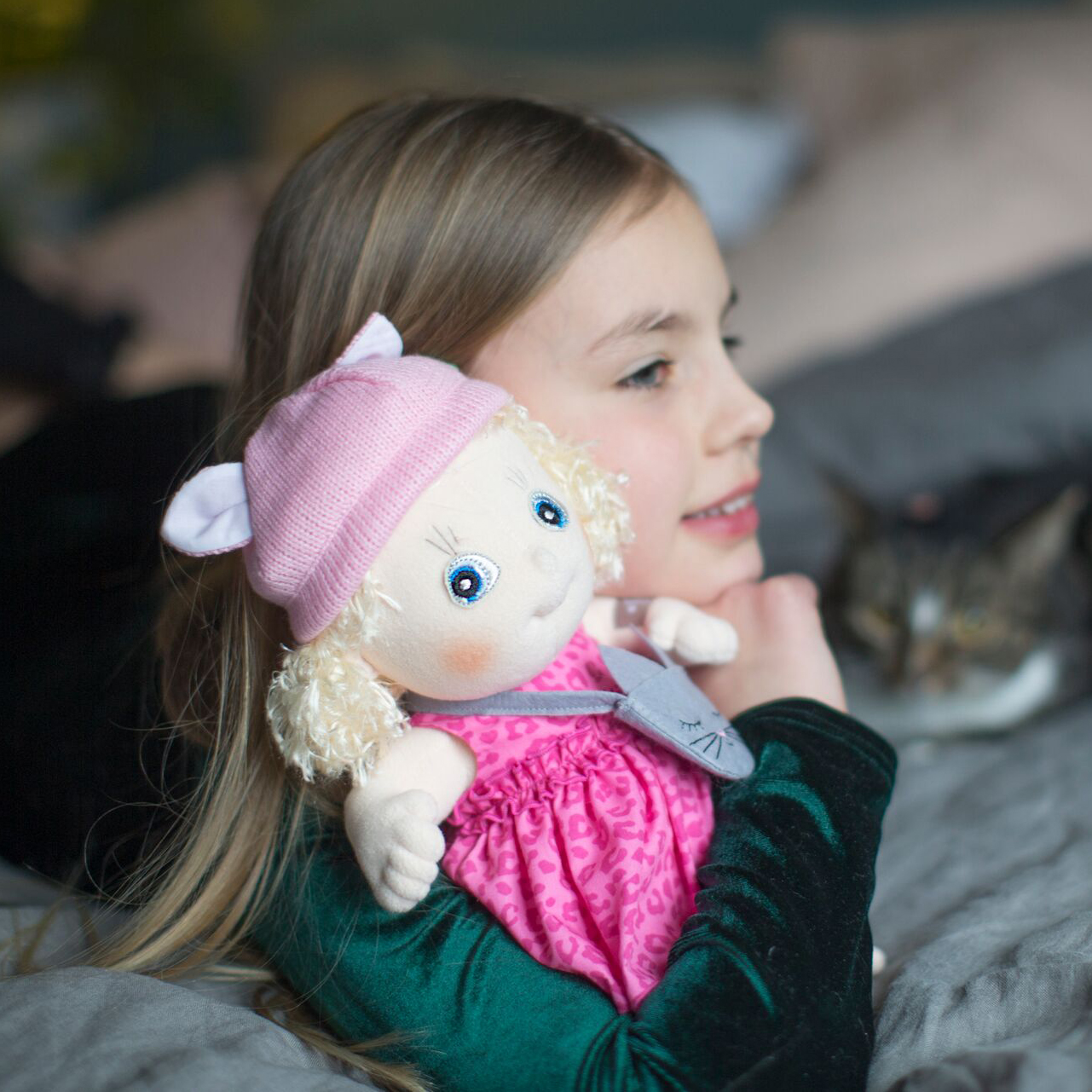 Child cuddling with the Rubens Cutie doll Emelie on the bed