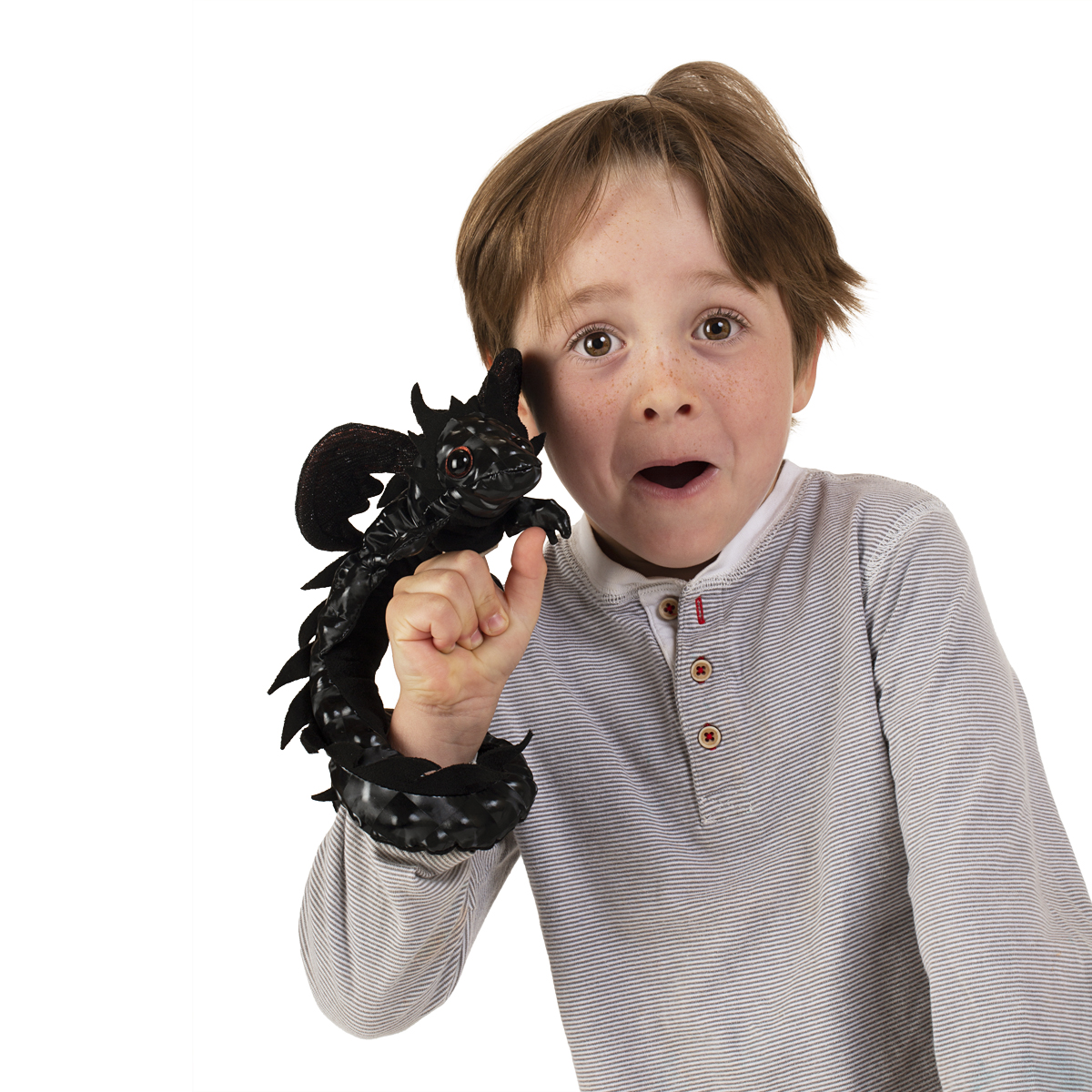 Junge hält eine schwarze Folkmanis Fingerpuppe Drachen Armband am ausgestreckten Zeigefinger, der Drachenschwanz ringelt sich ums Handgelenk
