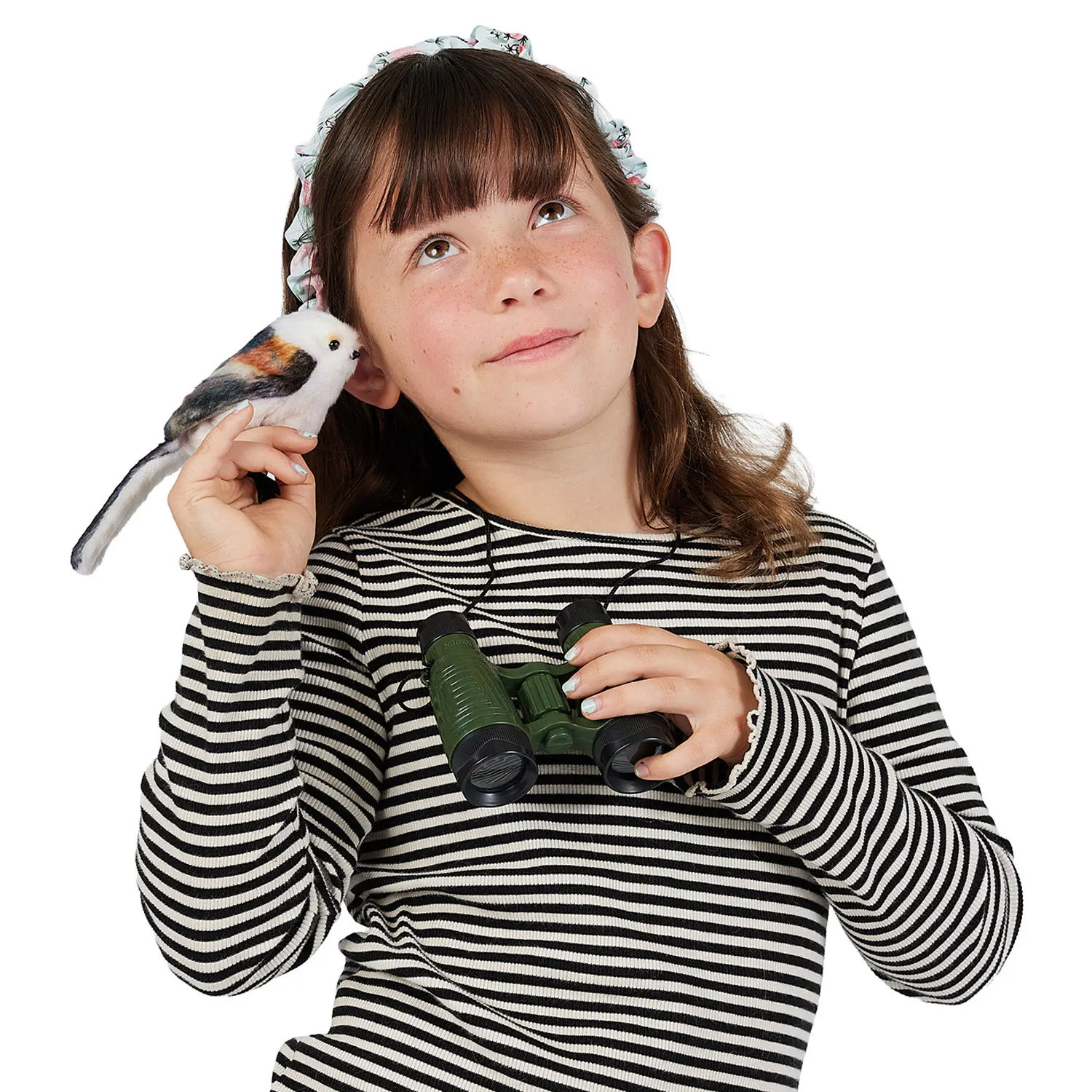 Girl holding a Folkmanis mini long-tailed tit finger puppet with white plumage and brown accents near her ear, green binoculars in her other hand