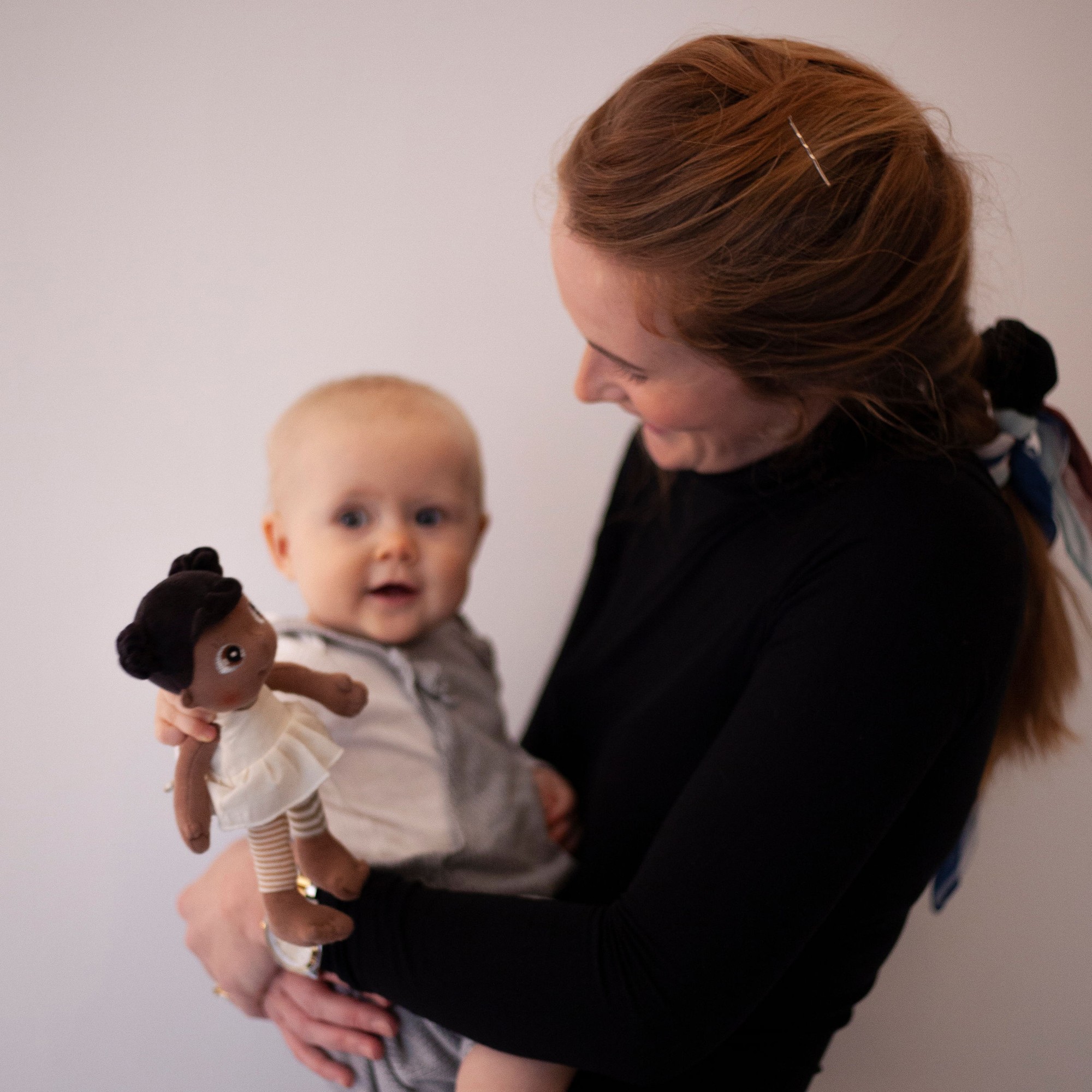 Frau zeigt einem Baby die Rubens EcoBuds Mini-Puppe Flora