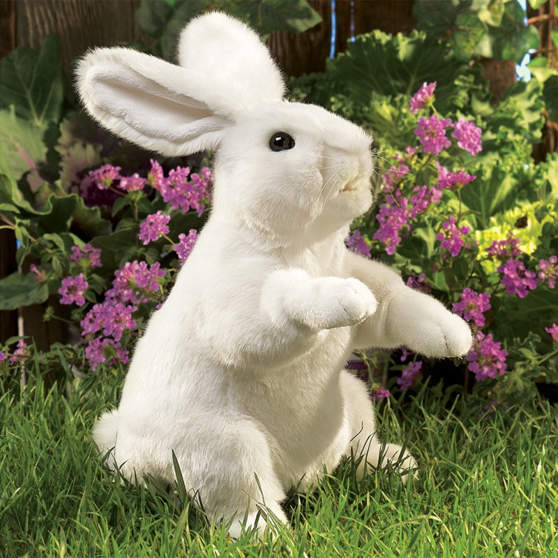 Folkmanis Handpuppe weißer Hase in aufrechter Pose auf Gras, vor lila Blüten, Seitenansicht