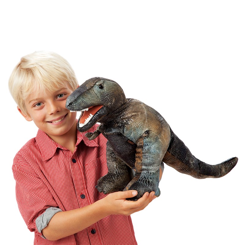 Junge hält Folkmanis Handpuppe kleiner Tyrannosaurus Rex mit geöffnetem Maul und detaillierter Schuppentextur in Grau-Grün-Braun.
