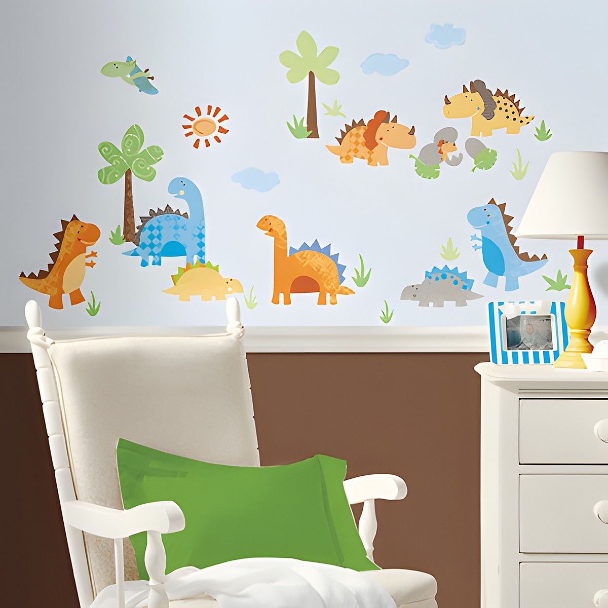 RoomMates wall decal Babysaurus, colourful dinosaur motifs with palm trees and a sun on a light blue children's room wall behind a rocking chair