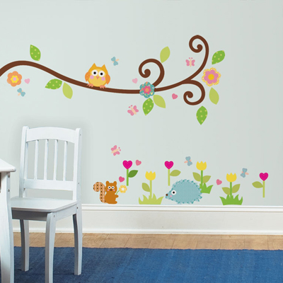 RoomMates Wandbild Happi Scroll Branch, geschwungener Ast mit Eule über Igel- und Eichhörnchen-Motiven an einer grauen Kinderzimmerwand neben einem weißen Stuhl