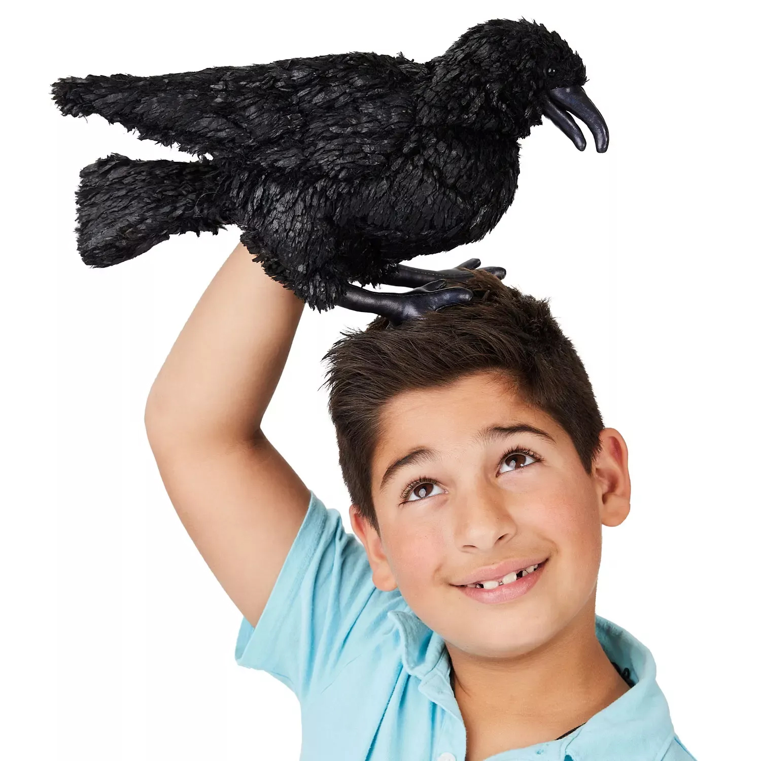 Junge hält Folkmanis Krähe Handpuppe mit schwarzem Gefieder und Krallen über seinen Kopf und schaut lächelnd hinauf