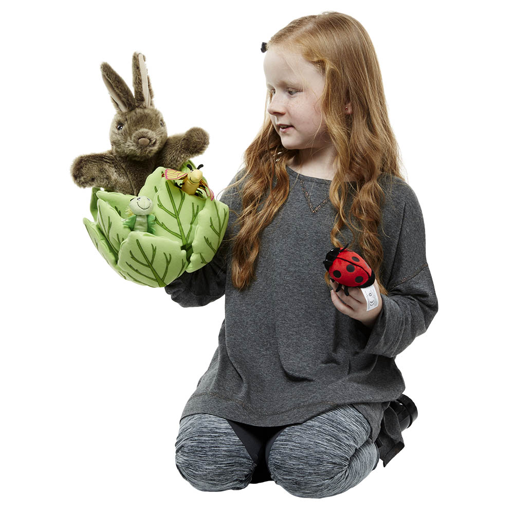 Mädchen hält die The Puppet Company Handpuppe Kaninchen im Kopfsalat und die Marienkäfer-Fingerpuppe