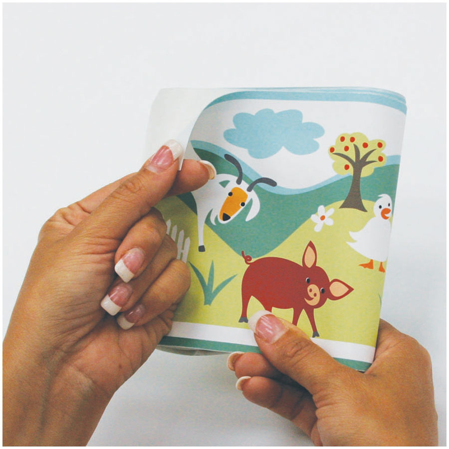 RoomMates border Gem's Friends Farm, hands folding the border strip with a goat and duck motif, usage example