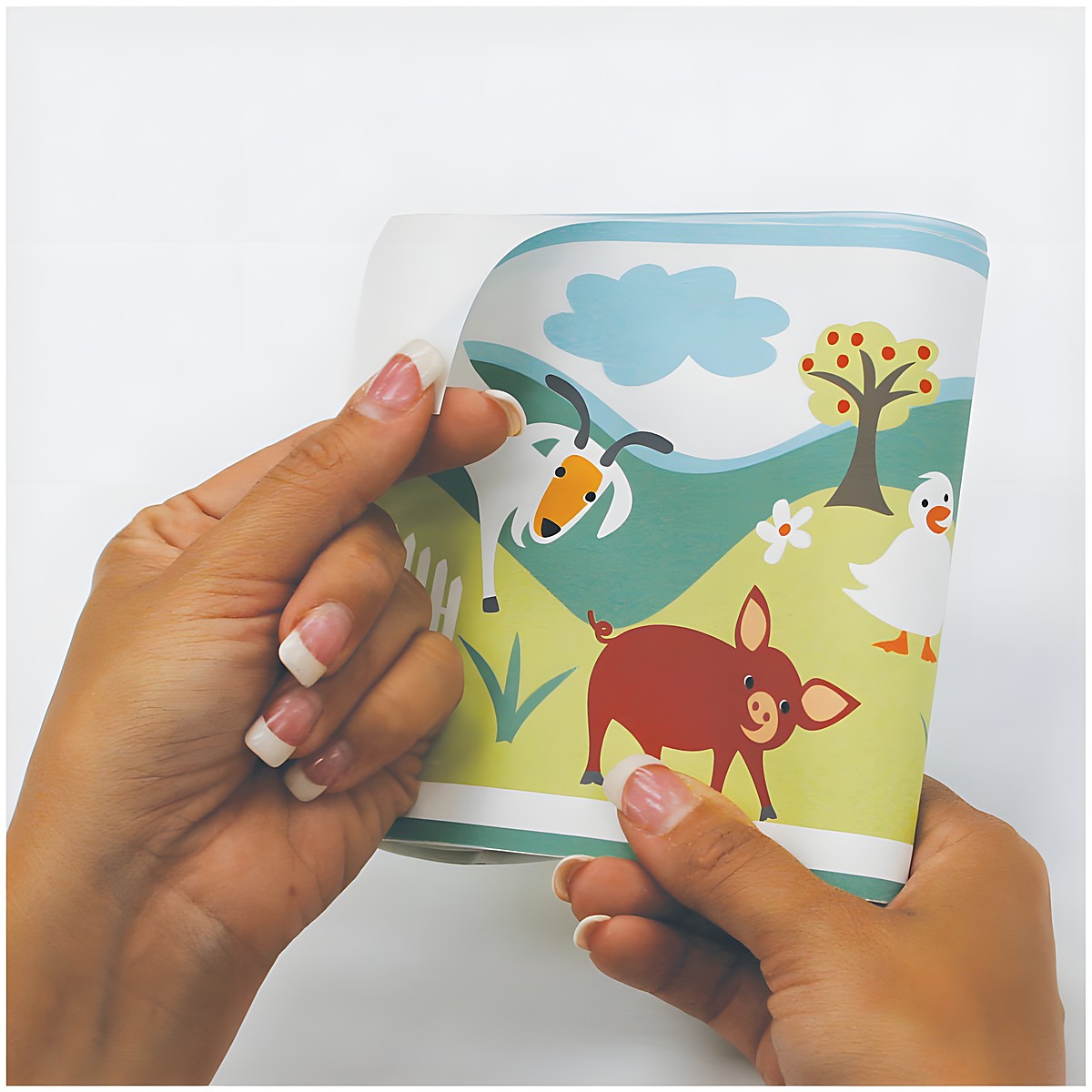 RoomMates border Gem's Friends Farm, hands folding the border strip with a goat and duck motif, usage example