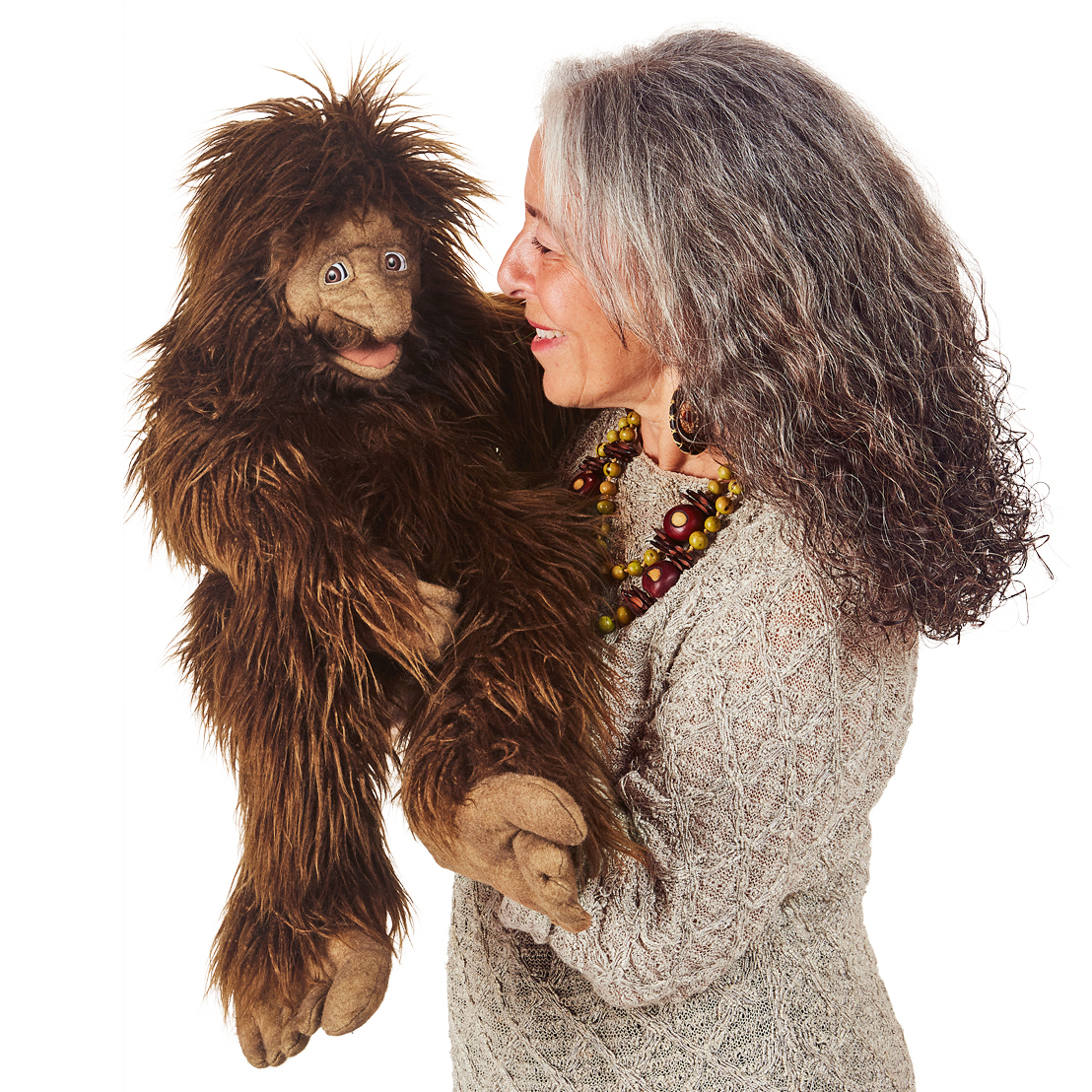 Folkmanis Handpuppe Bigfoot mit zottigem braunem Fell, von einer Frau geführt, die der Puppe lächelnd ins Gesicht schaut