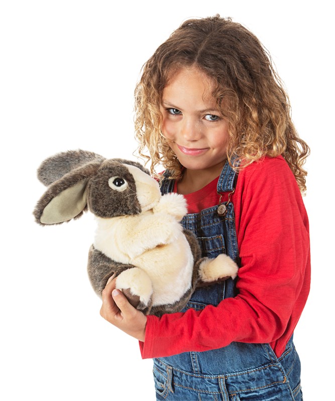 Mädchen hält Folkmanis Handpuppe Hase Holländer mit grau-weißem Fell und hängenden Ohren in beiden Armen