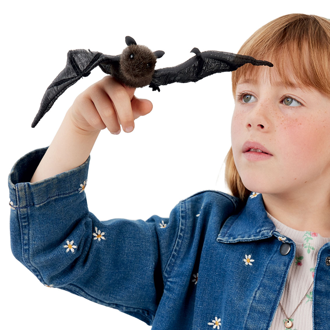 Folkmanis mini bat finger puppet with outstretched black wings on a girl's finger