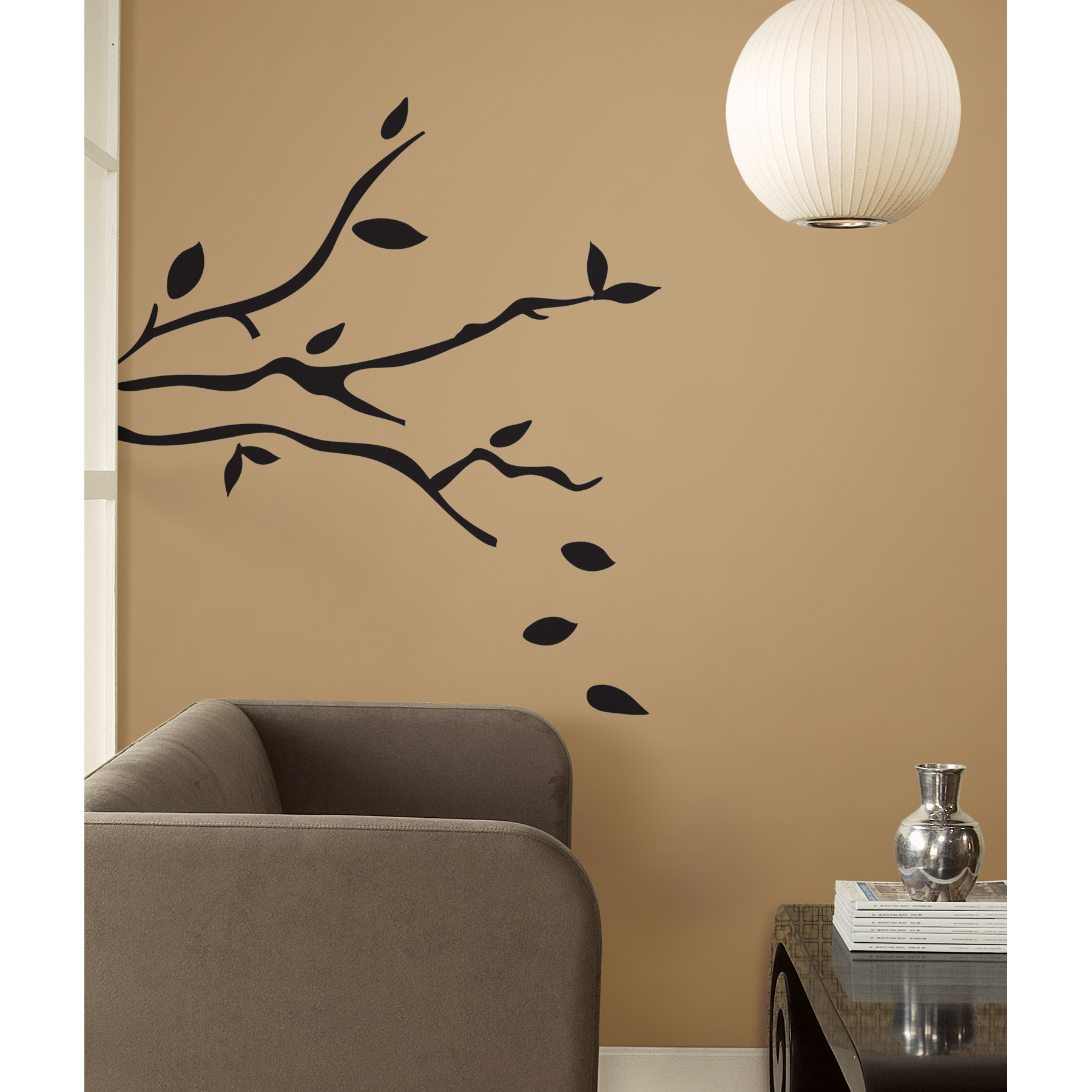 RoomMates Wandbild Tree Branches, schwarzer Ast mit fallenden Blättern an einer braunen Wand neben einem Sessel