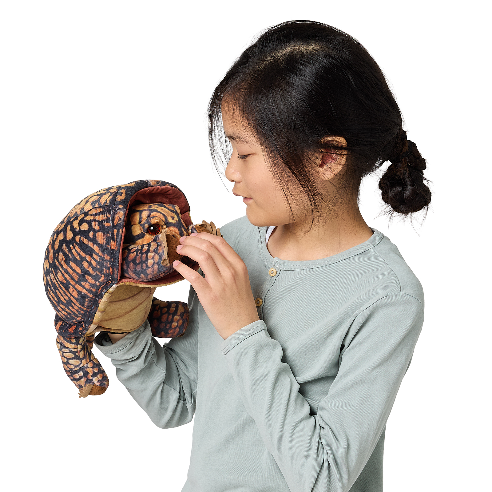 Girl operating a Folkmanis box turtle hand puppet with open mouth and brown-black scale pattern, side view
