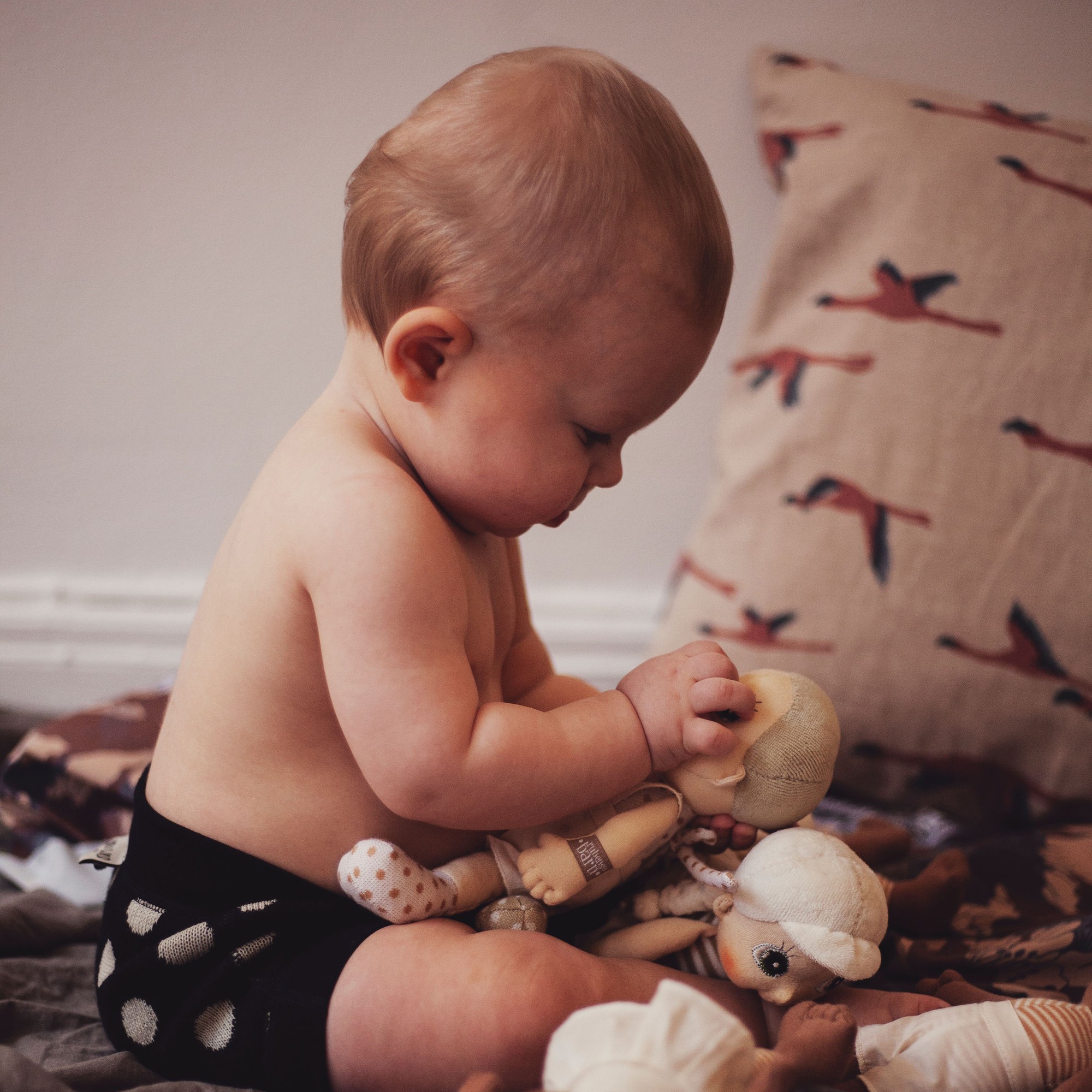 Baby looking at a Rubens EcoBuds mini doll while playing