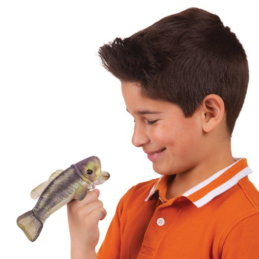 Junge im orangefarbenen Polo-Shirt hält Folkmanis Fingerpuppe mini Forellenbarsch auf dem Finger und lächelt sie an.