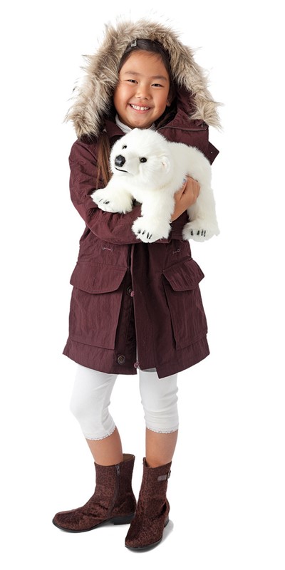 Girl holding a white Folkmanis polar bear cub hand puppet in her arms and smiling at the camera