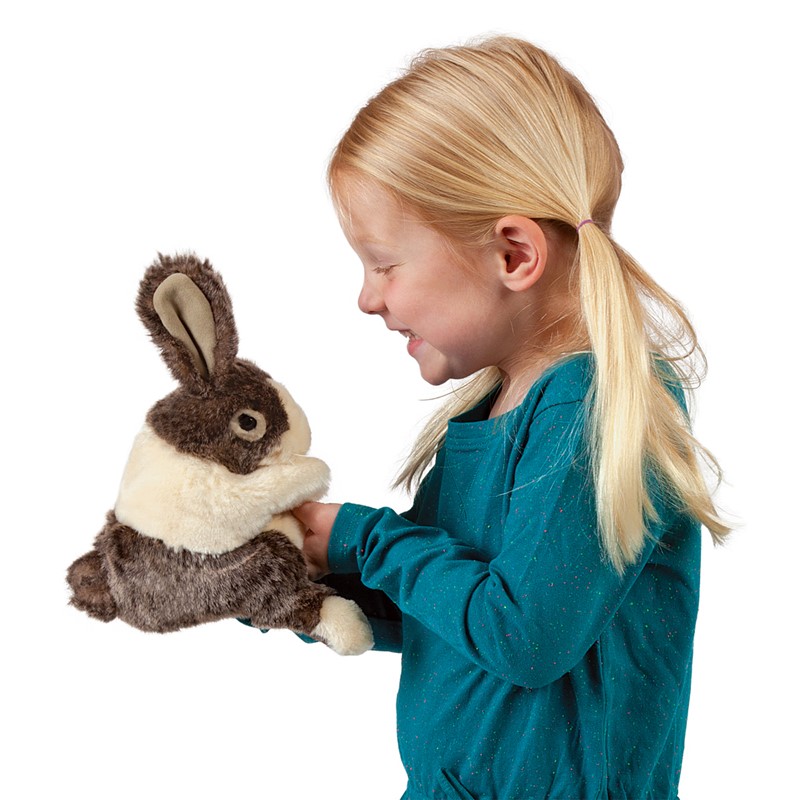 Mädchen führt die Folkmanis Handpuppe Hasenbaby Holländer mit braun-cremefarbenem Fell von unten mit der Hand