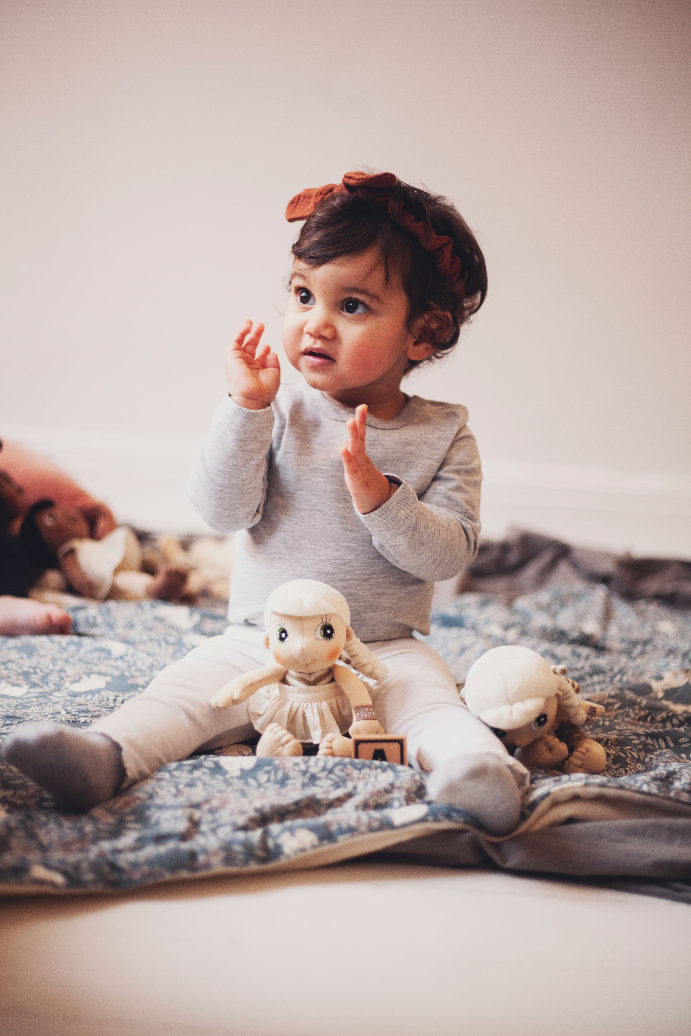 Kleinkind spielt mit der Rubens EcoBuds Mini-Puppe Lily auf einer Decke