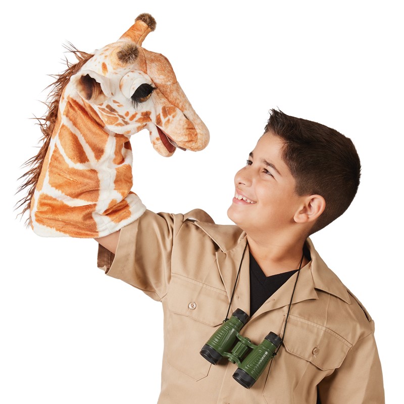 Boy in safari outfit holds the Folkmanis giraffe hand puppet with brown-and-white spot pattern high above his head