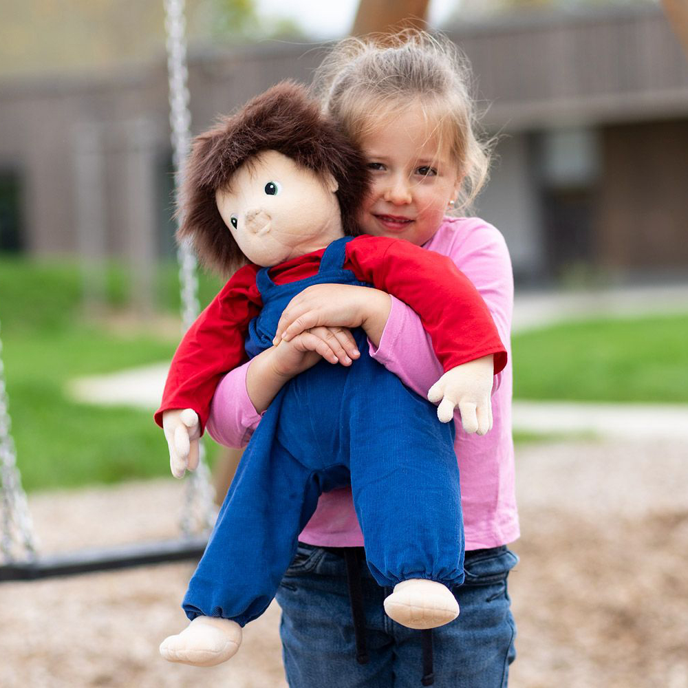 Kind trägt die Joyk Empathiepuppe Johan auf dem Spielplatz