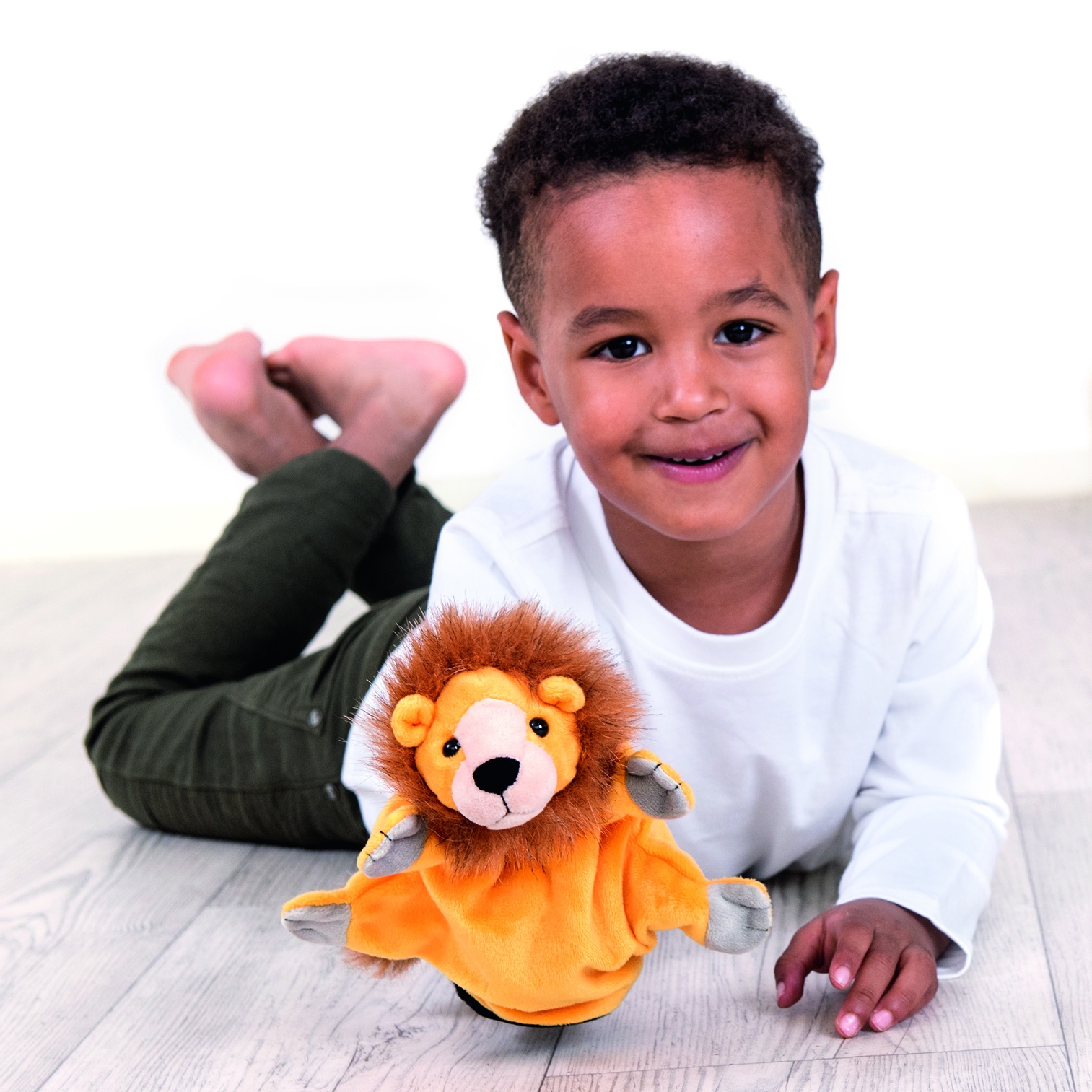 Junge liegt auf dem Boden mit der Beleduc Handpuppe Löwe, Anwendungsbeispiel