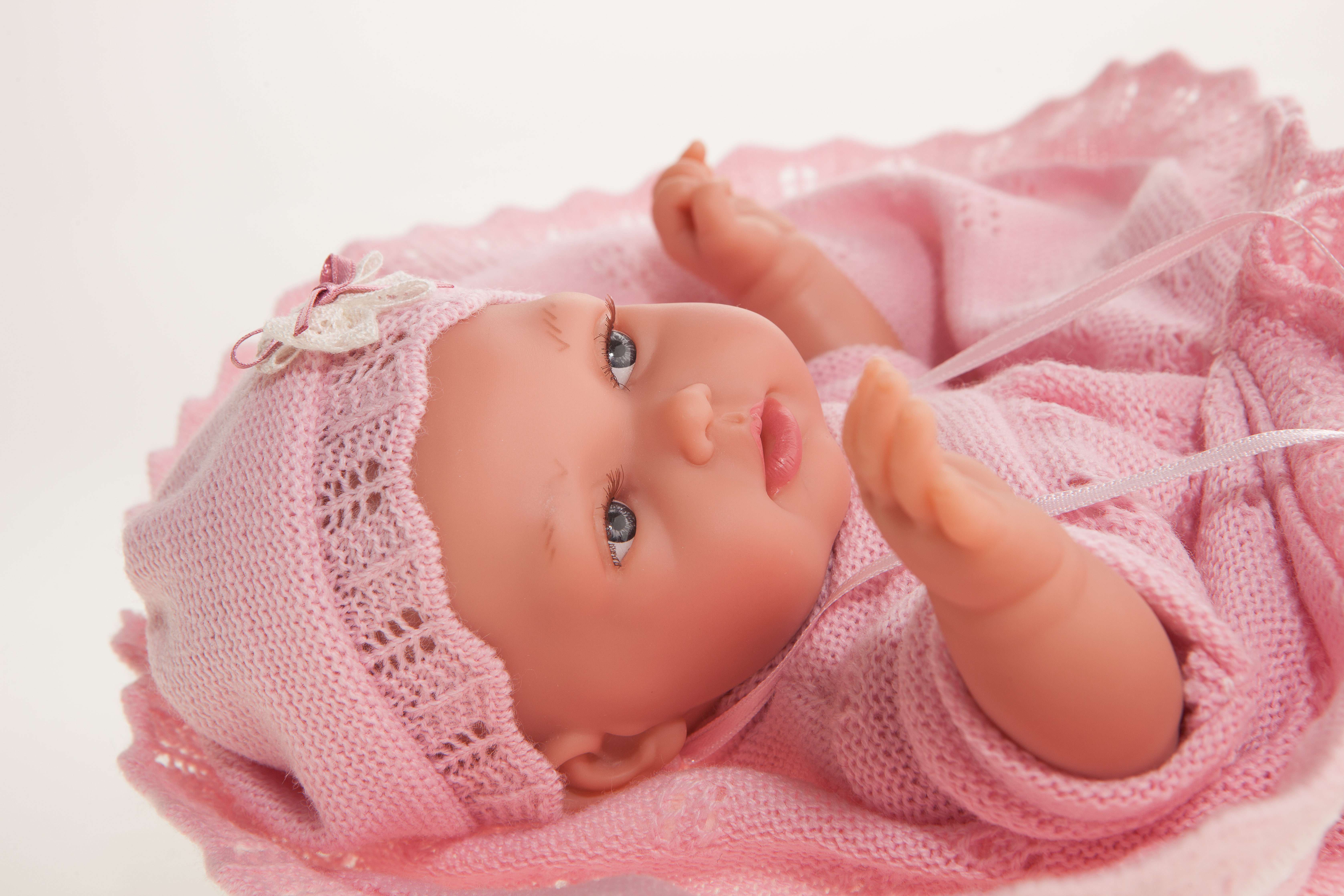 Antonio Juan Babypuppe Peke, Nahaufnahme des liegenden Gesichts mit rosa Mütze, Hand nah am Mund