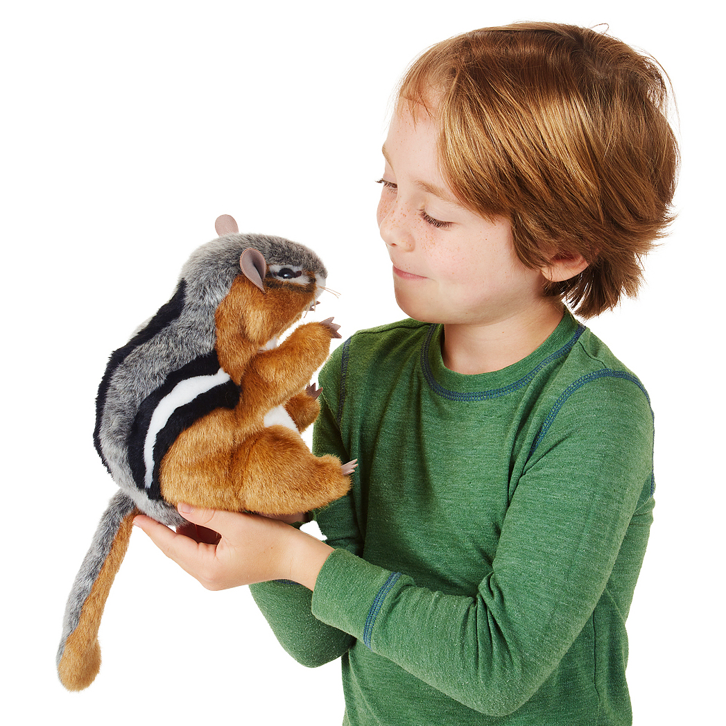 Junge hält die Folkmanis Handpuppe Streifenhörnchen mit braun-grau-schwarz gestreiftem Fell in beiden Händen und schaut sie lächelnd an.