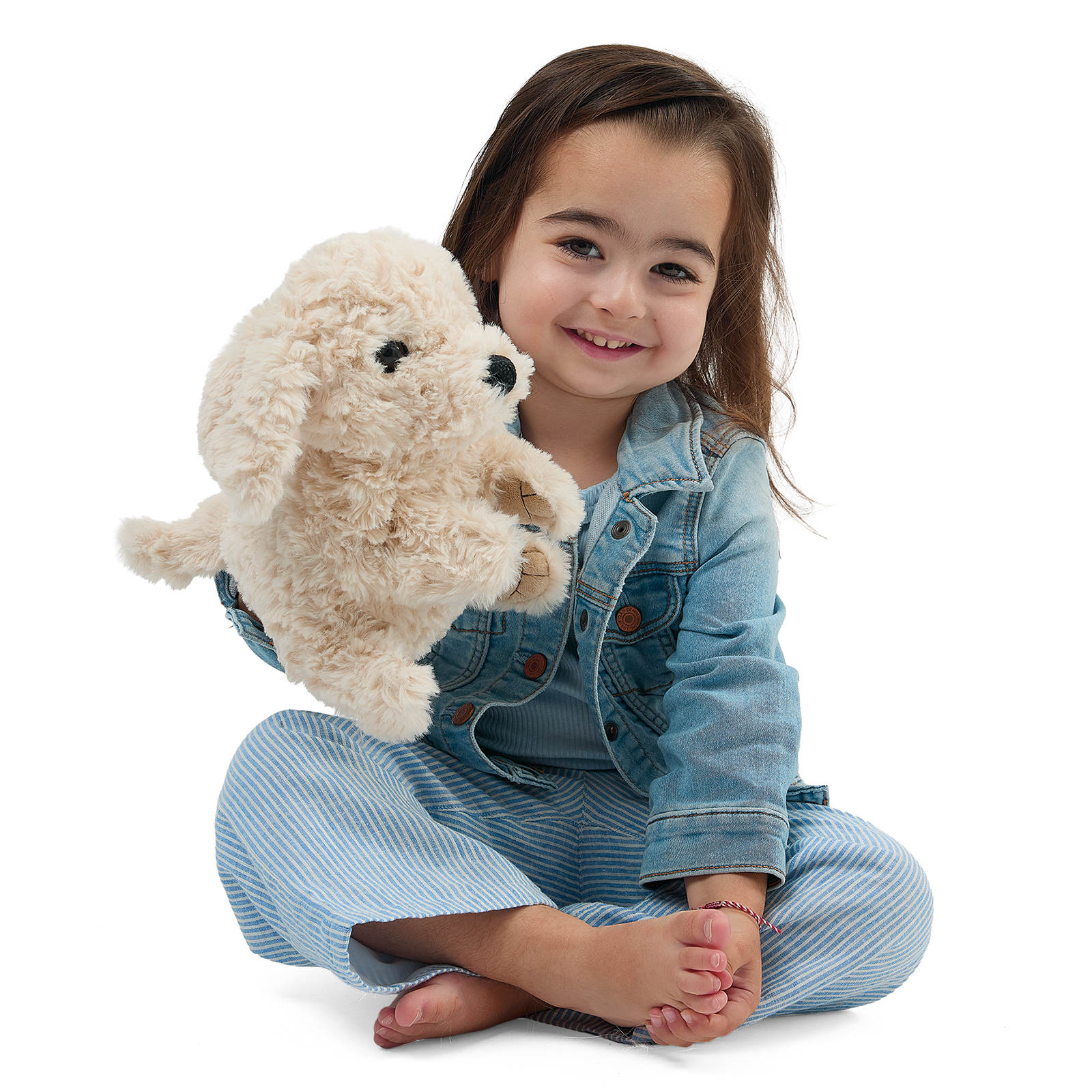 Folkmanis puppy hand puppet sitting beside a smiling toddler, its mouth closed.