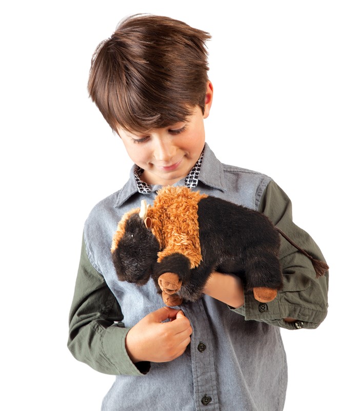 Boy holding a Folkmanis small bison hand puppet with brown and black fur and horns in both hands