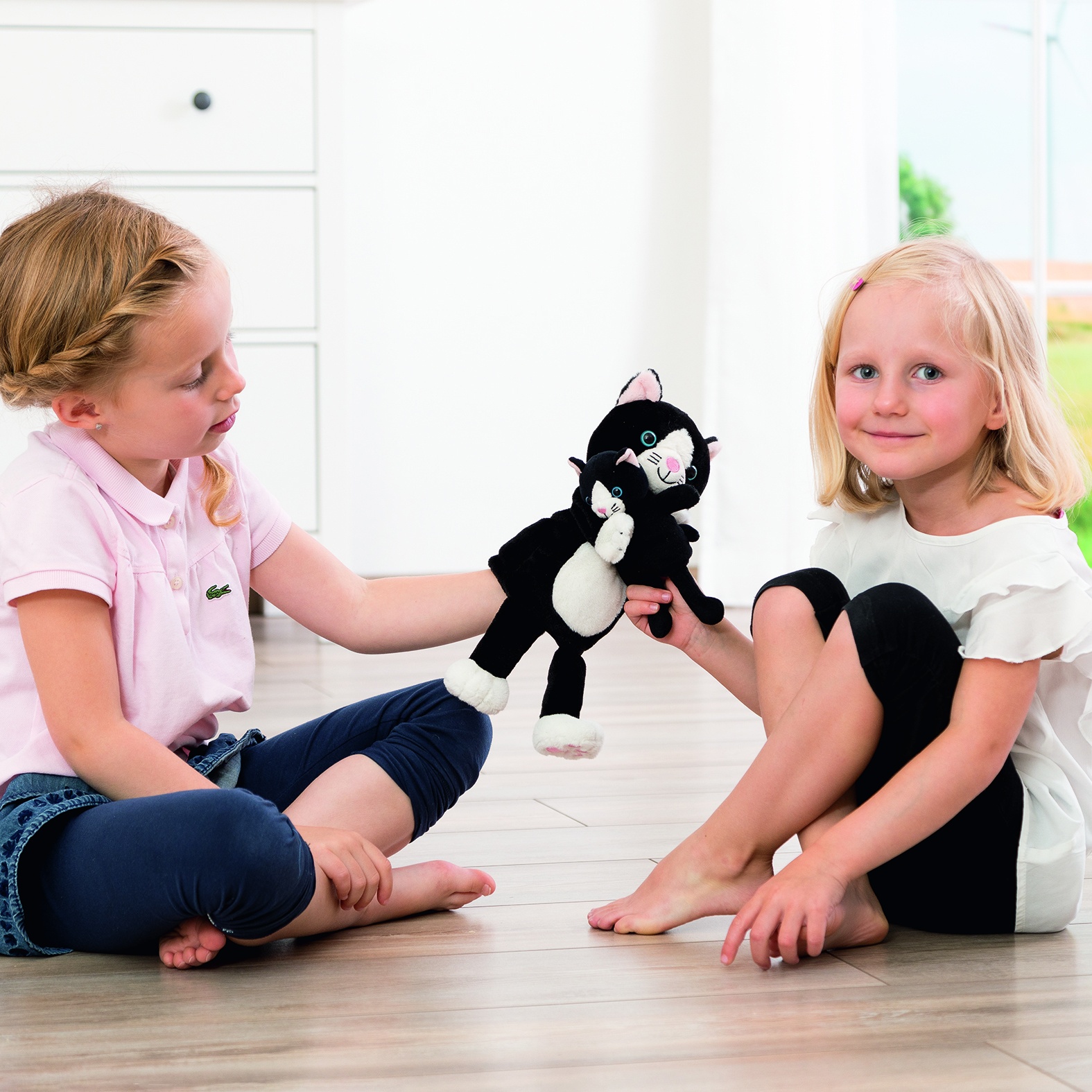 Two girls playing with the Beleduc story hand puppet cat Cara and finger puppet Mimi, usage example
