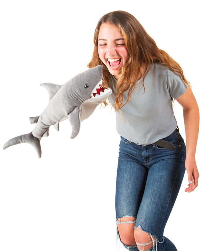 Lachende Teenagerin wird von grauer Folkmanis Hai-Handpuppe mit roten Zähnen am Bauch gepackt
