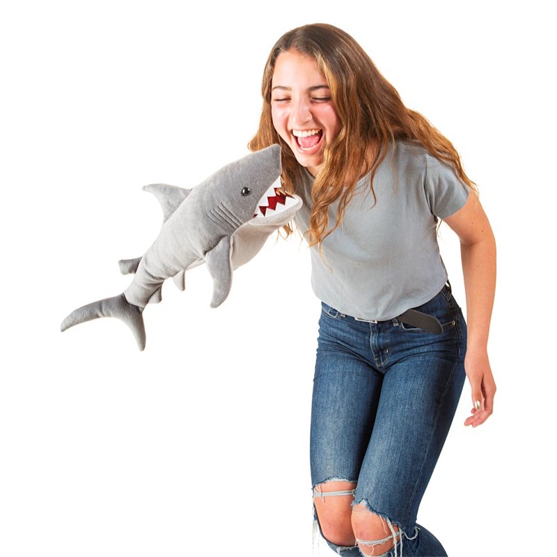 Lachende Teenagerin wird von grauer Folkmanis Hai-Handpuppe mit roten Zähnen am Bauch gepackt