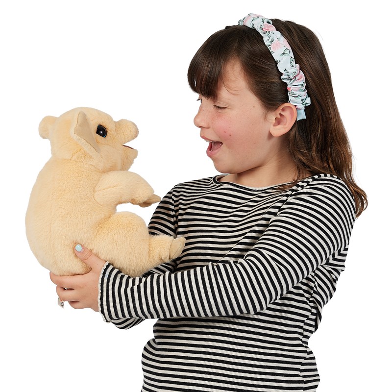 Mädchen hält cremefarbene Folkmanis Handpuppe Schweinchen mit geöffnetem Maul in beiden Händen und lacht