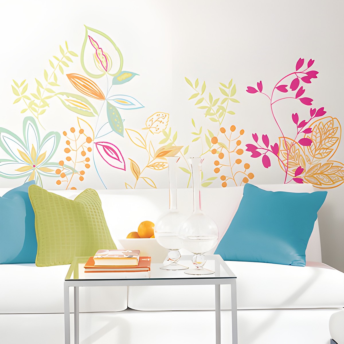 RoomMates wall decal Graphic Leaves, colourful graphic leaf and blossom vines in green, pink and orange on a white wall above a sofa