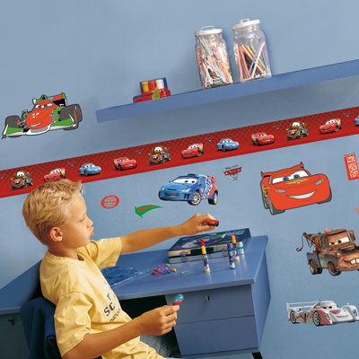 decofun Wanddekoration Pixar Cars 2 an blauer Kinderzimmerwand mit roter Bordüre, Junge am Schreibtisch mit Rennwagen Francesco Bernoulli darüber
