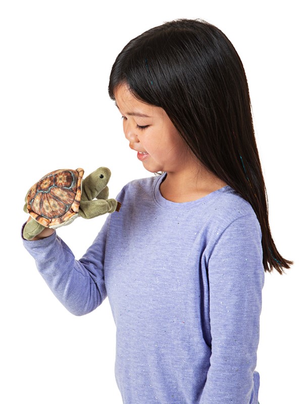 Mädchen führt Folkmanis Fingerpuppe mini Landschildkröte mit gemustertem Panzer an der Hand, Seitenansicht