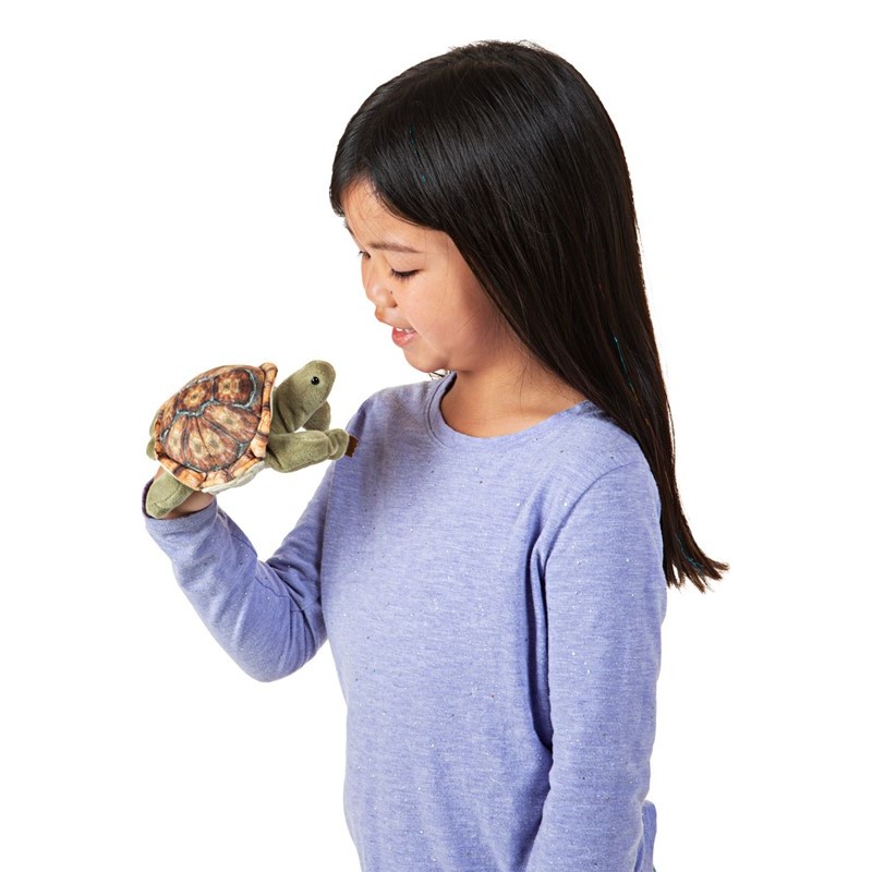Mädchen führt Folkmanis Fingerpuppe mini Landschildkröte mit gemustertem Panzer an der Hand, Seitenansicht