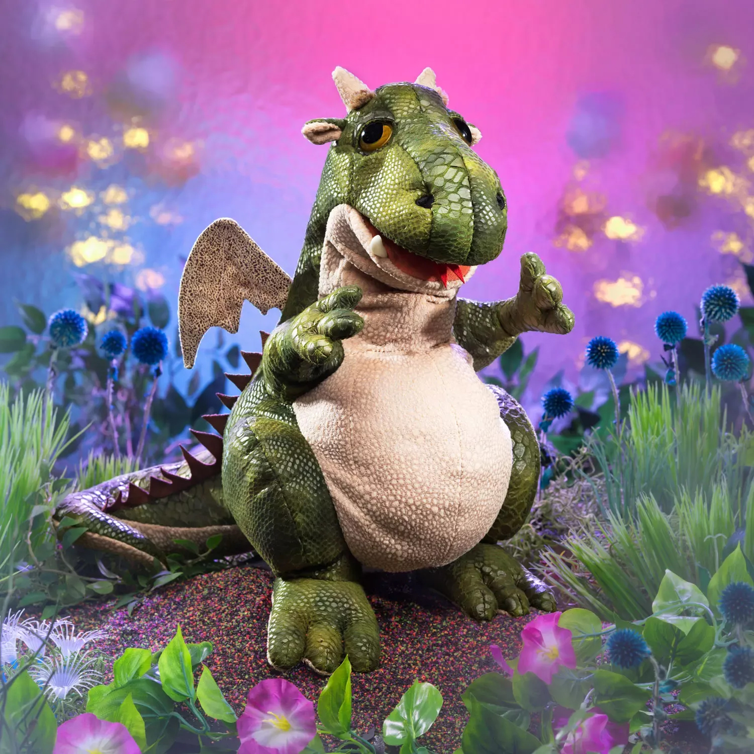 Folkmanis hand puppet green dragon with open mouth, beige belly and wings, sitting front-facing against a pink background