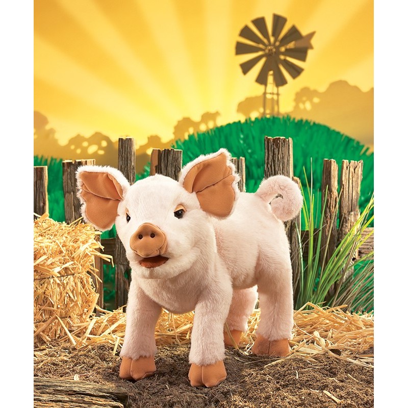 Folkmanis piglet hand puppet in pink, standing with open mouth, in front of hay bales and a farm backdrop