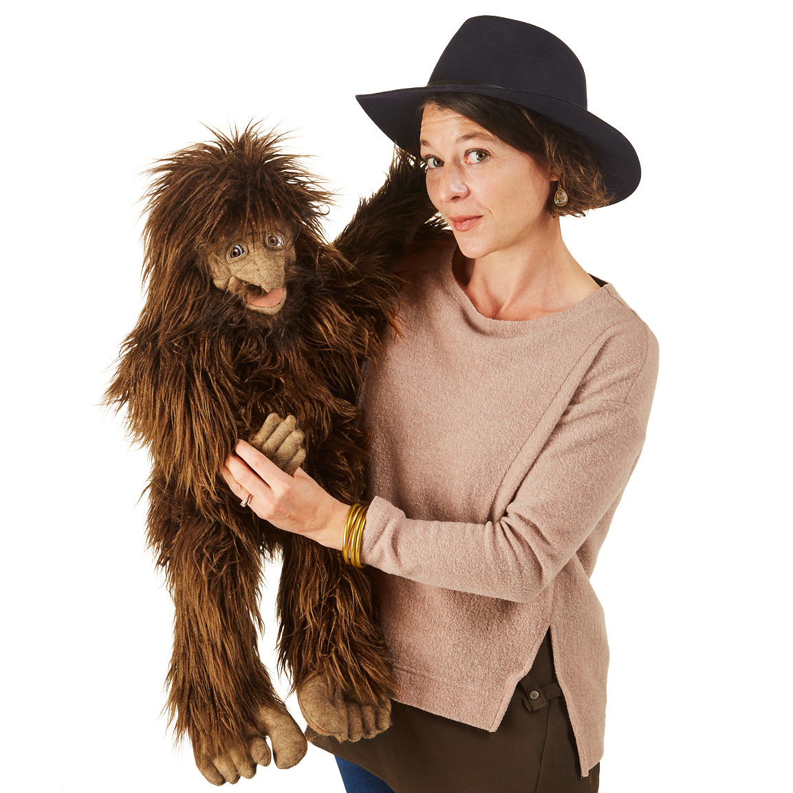 Folkmanis Handpuppe Bigfoot mit zotteligen braunen Fell, von einer Frau mit Hut in der Hand geführt, Ganzkörperansicht