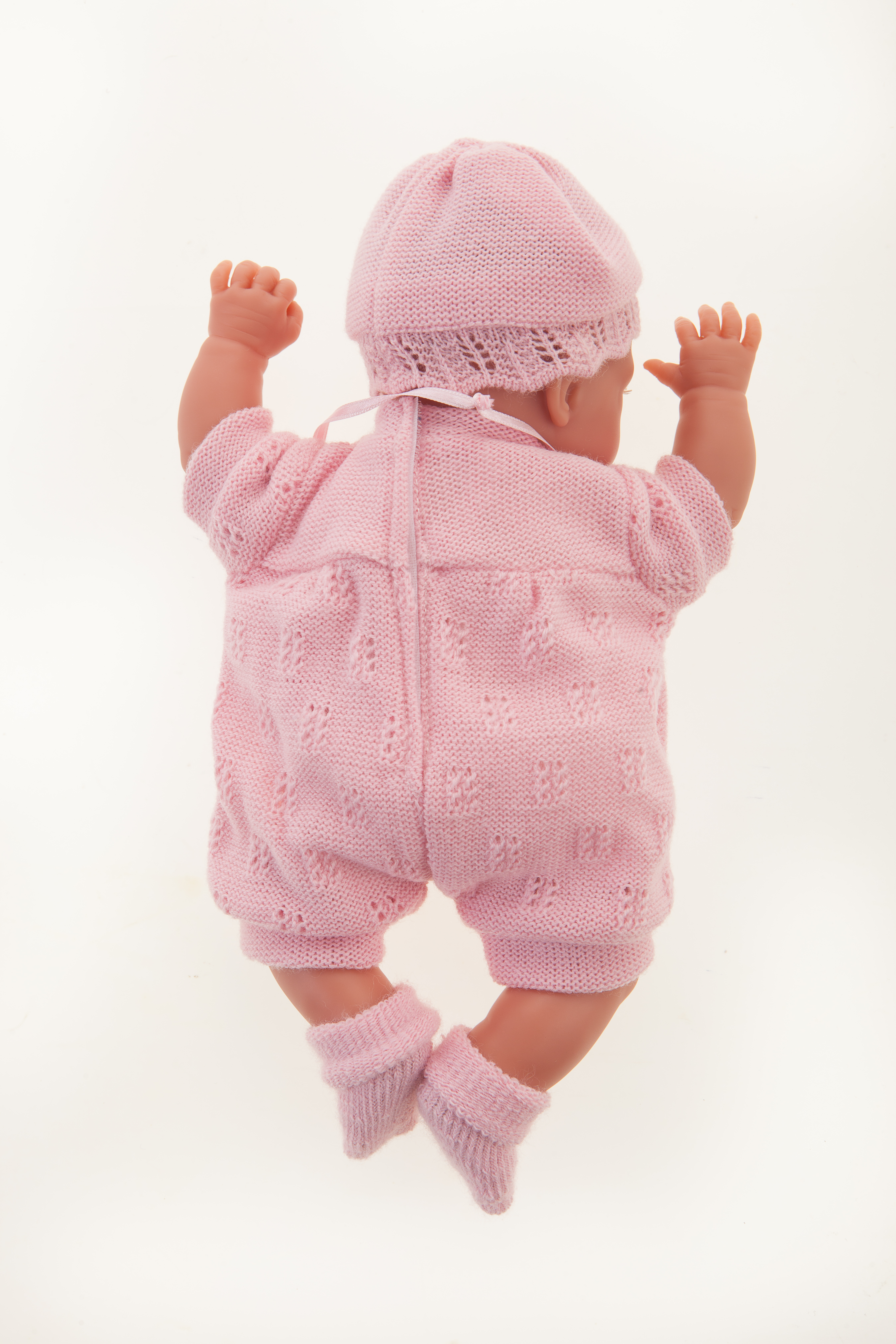 Antonio Juan Babypuppe Peke, realistische Puppe im rosa Strickset von hinten, beide Ärmchen nach oben gestreckt