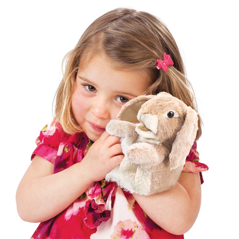 Mädchen hält Folkmanis Handpuppe kleines Widderkaninchen in beigem Plüsch mit langen Schlappohren an die Wange