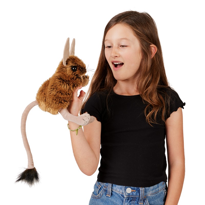 Girl holding a Folkmanis jerboa hand puppet with brown plush fur, long ears and a thin tail on her hand