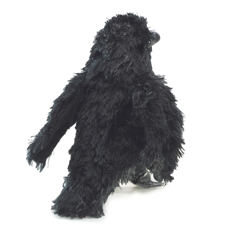 Folkmanis mini raven finger puppet made of black shaggy plush in an upright pose, shown from a side angle