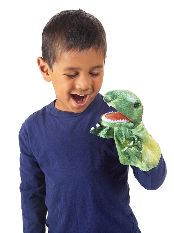 Junge lacht, während er eine grüne Folkmanis Handpuppe kleiner T-Rex mit geöffnetem Maul und weißen Zähnen auf der Hand trägt.